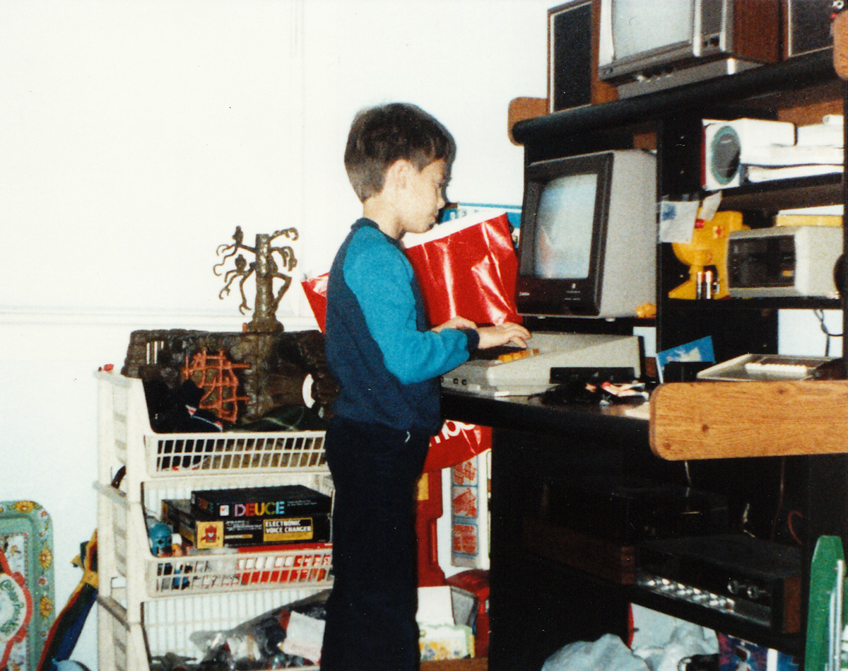 Adam as a child in front of a vintage personal computer